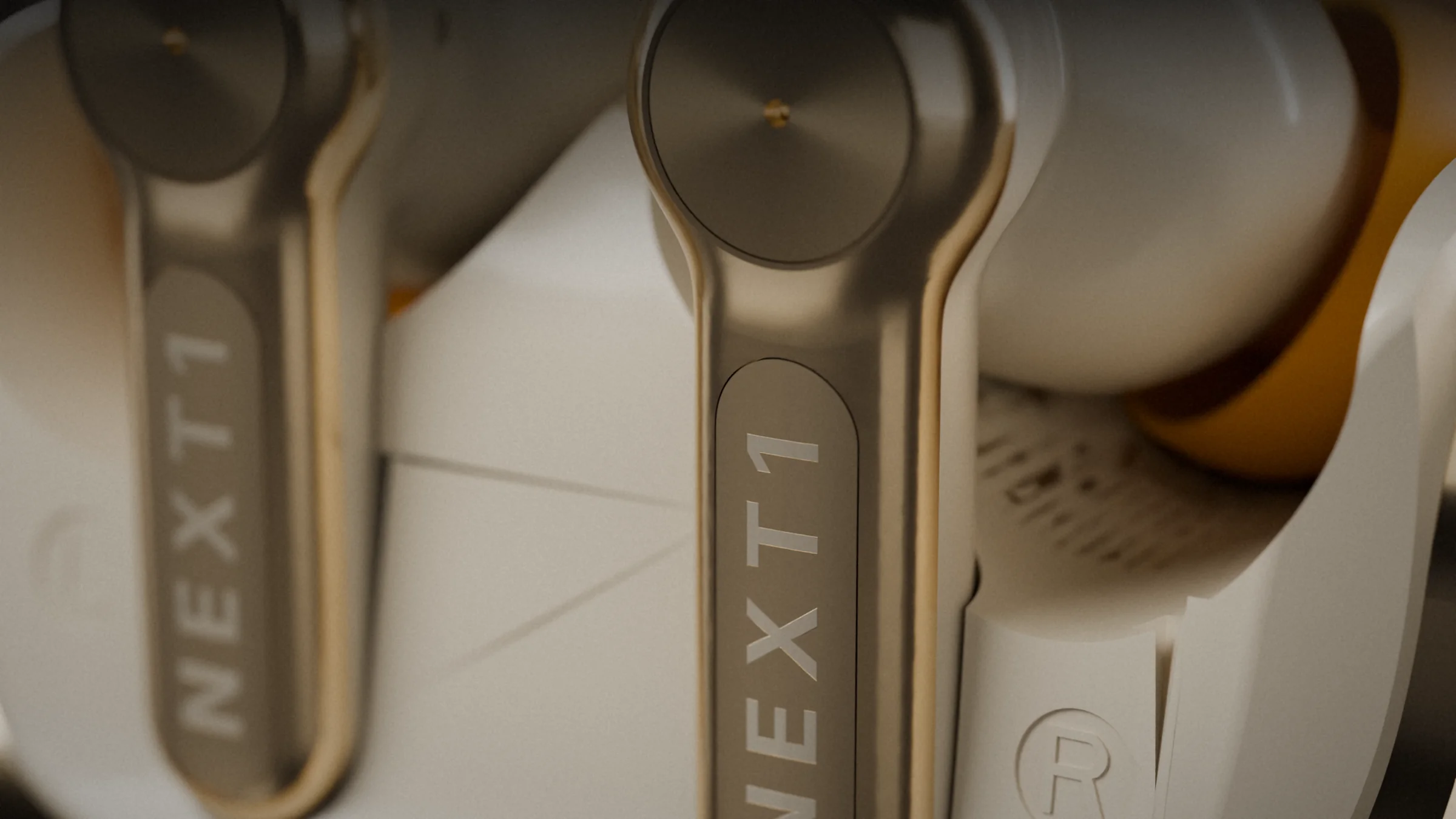 Both NEXT1 earbuds seated in the case, the engraved gold stems in focus